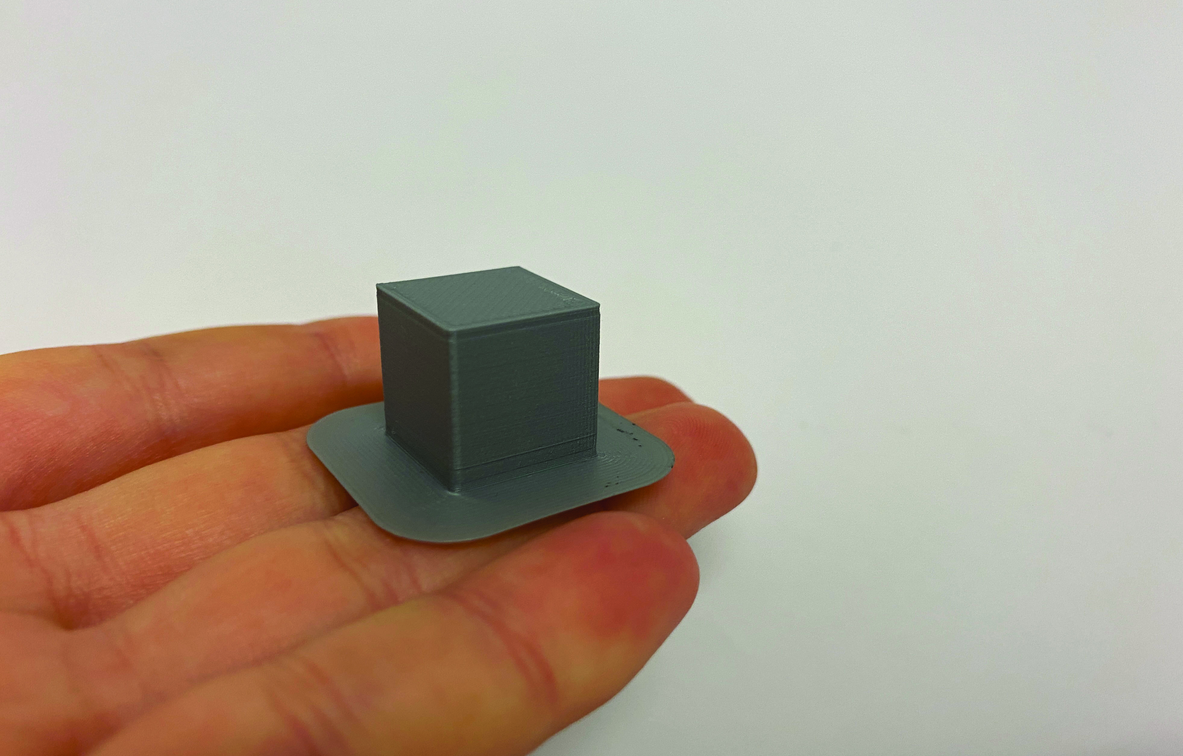 3D printed grey cube on a hand