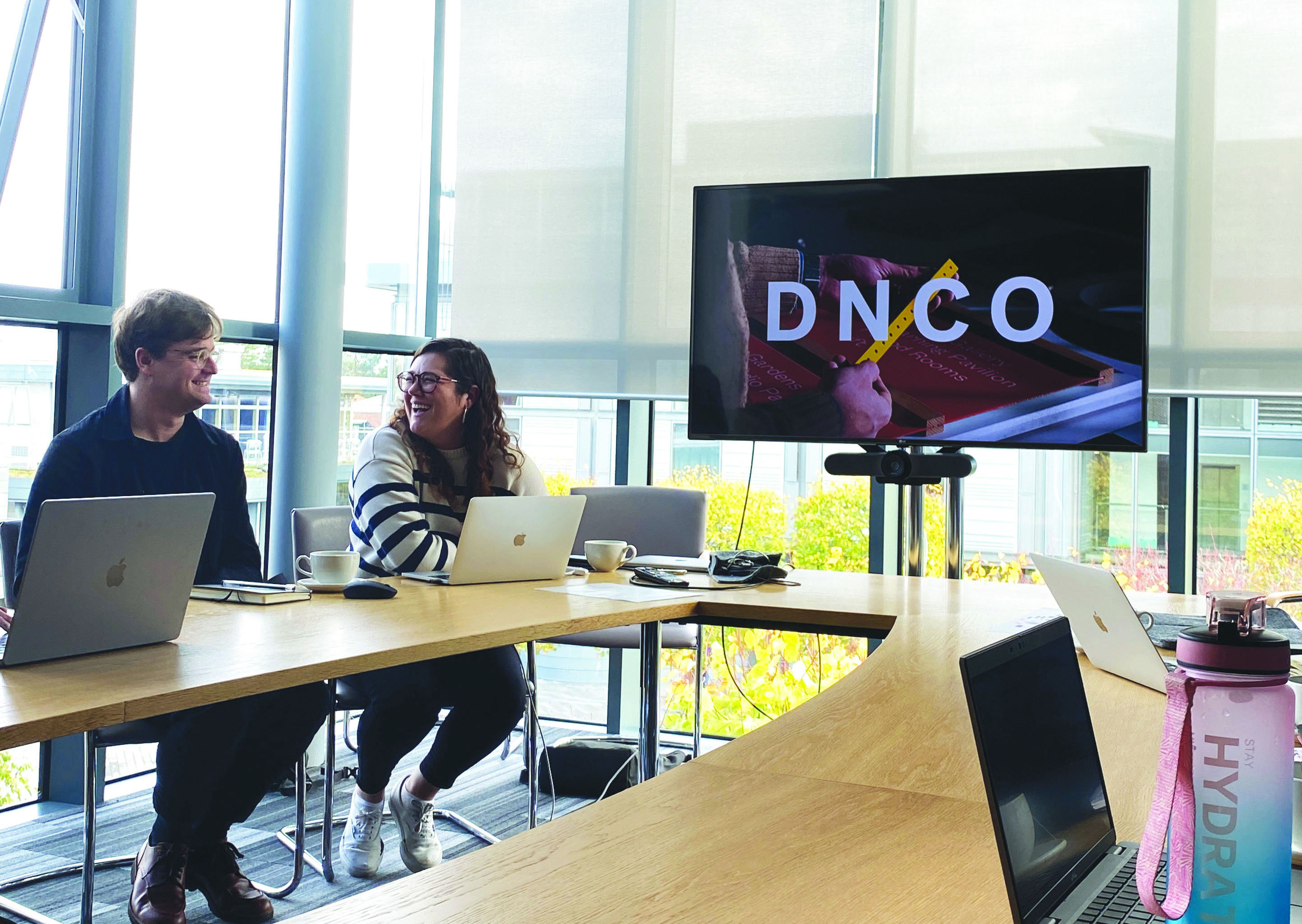 a photograph of a meeting table with dnco on the screen